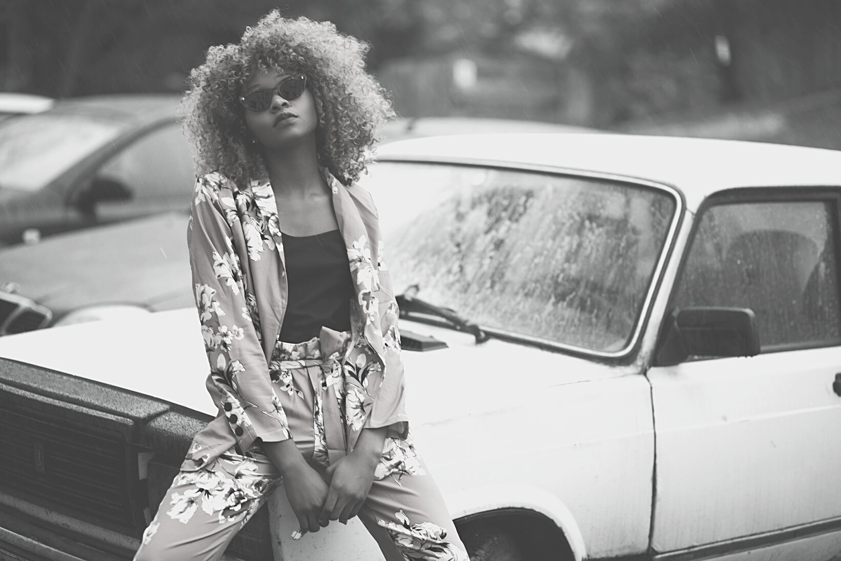 Woman Wearing Brown Floral Print Coat and Pants Sitting on Car